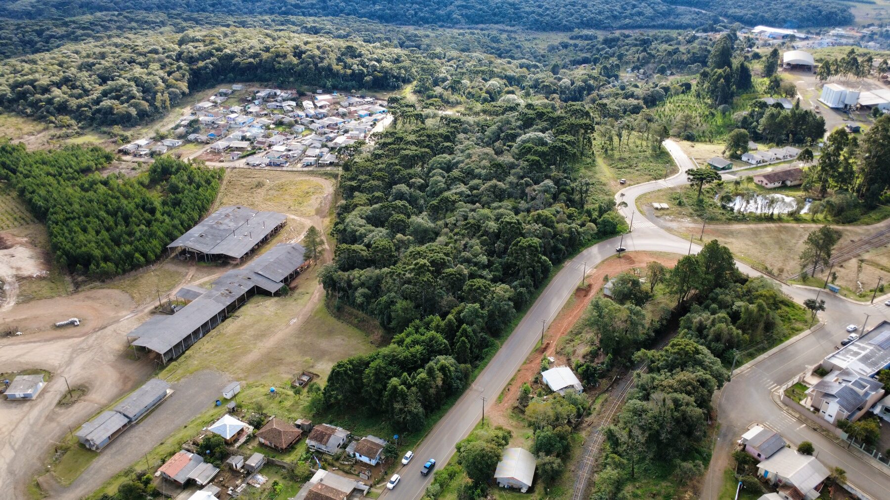 Vista aérea de estrada e ocupação urbana ao lado de remanescente florestal